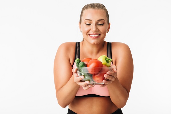 Donna sportiva con frutta e verdura.